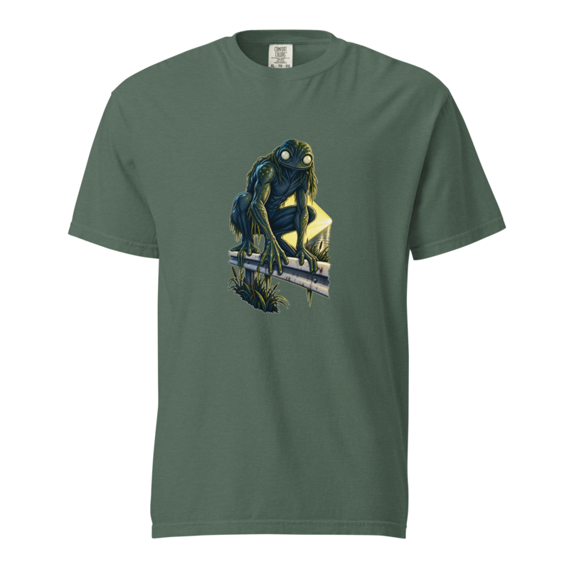 Loveland Frogman crouched on a highway guardrail with pale round eyes and a lit river behind, printed on a blue spruce heavyweight tee.